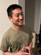 Man in green t shirt (Matthew Zhao) looks off camera.