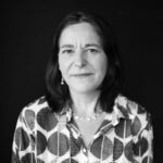 Black-and-white photo of a woman with dark hair in a button-down blouse looking at the camera.