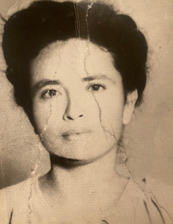 An old, sepia-tone photograph of a woman with dark hair looking directly at the camera.